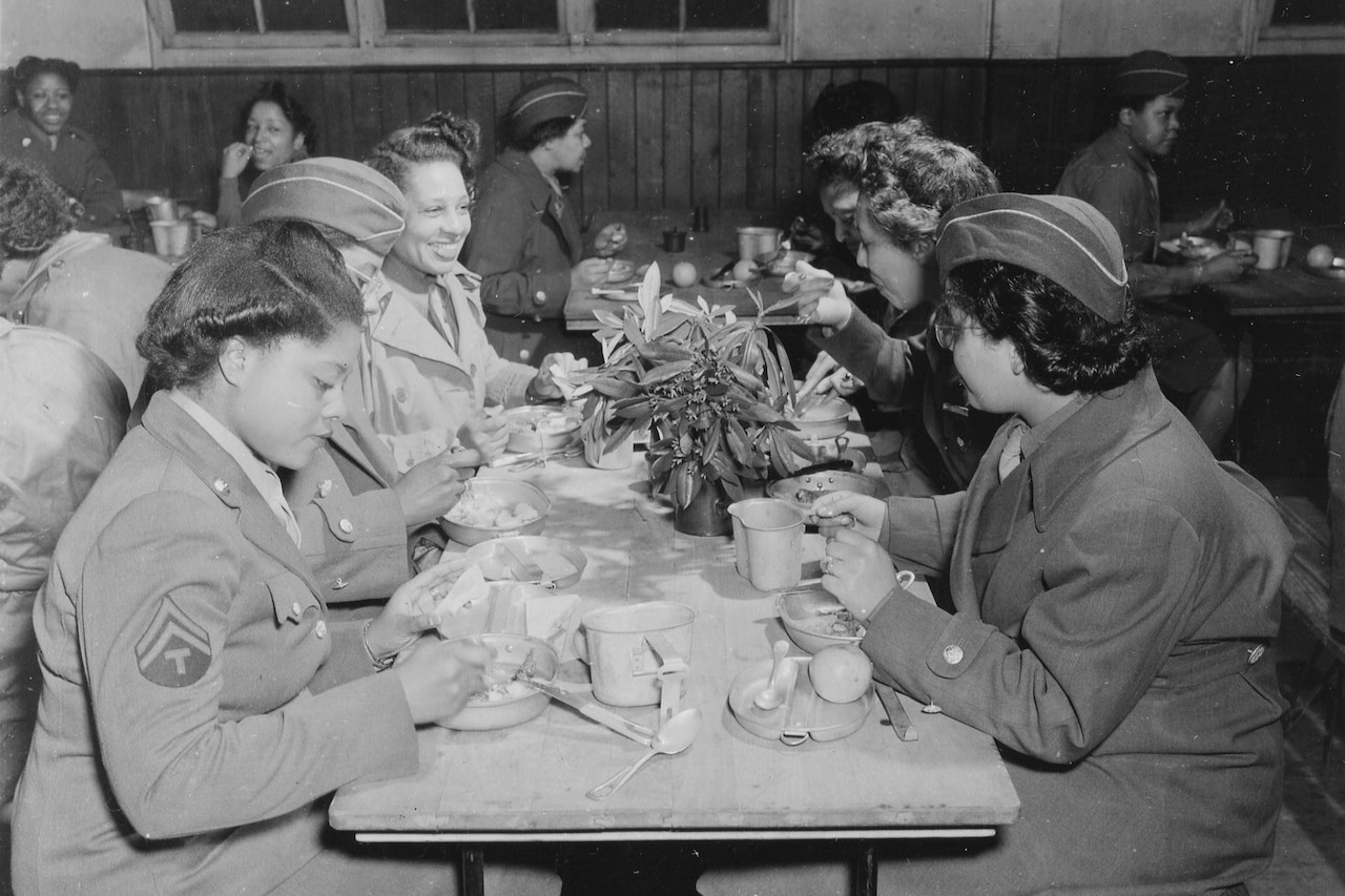 Several women sit around lunch tables eating.