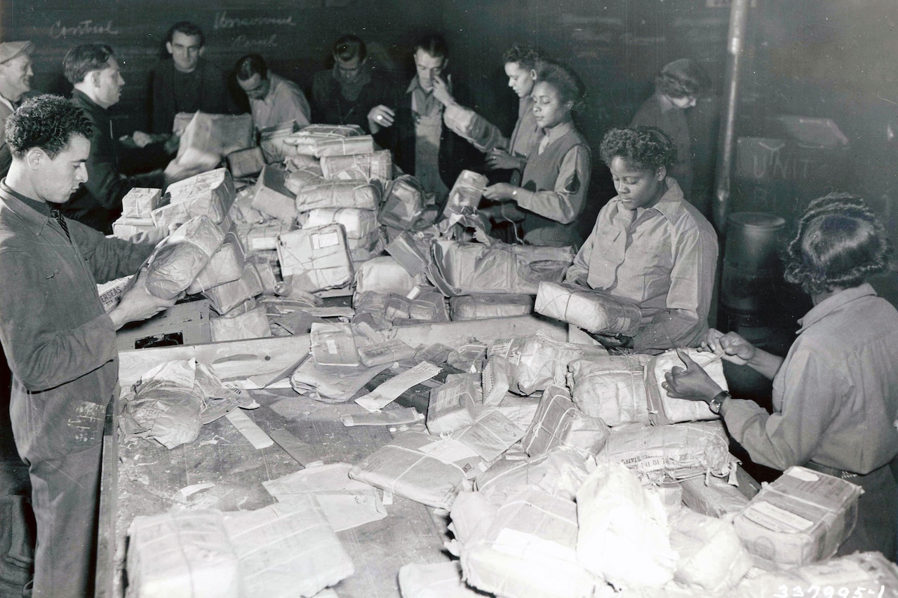 Several people handle parcels in a large bin.