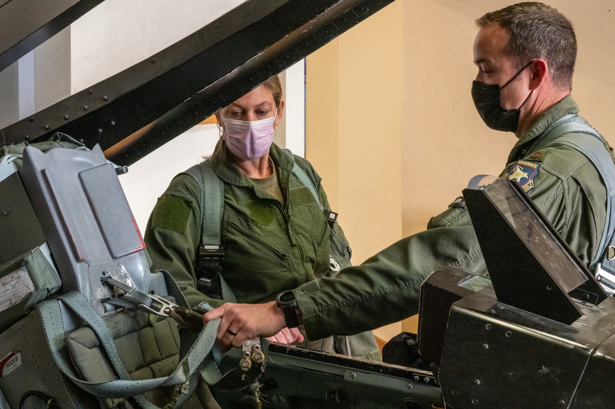 Maj. Philip Downing, 370th Flight Test Squadron, F-16 Test Pilot, demonstrates some of the flight safety equipment of an F-16 Fighting Falcon to Laura Macaluso