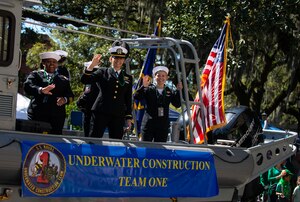 Yeoman 1st Class Jazzette Bailey, left, Ens. Amanda Clark and Logistics Specialist Seaman Ariel Watts, U.S. Navy Fleet Outreach Ambassadors, wave to spectators from the Underwater Construction Team One float during the St. Patrick’s Day Parade in Savannah, Ga., March 14, 2022.