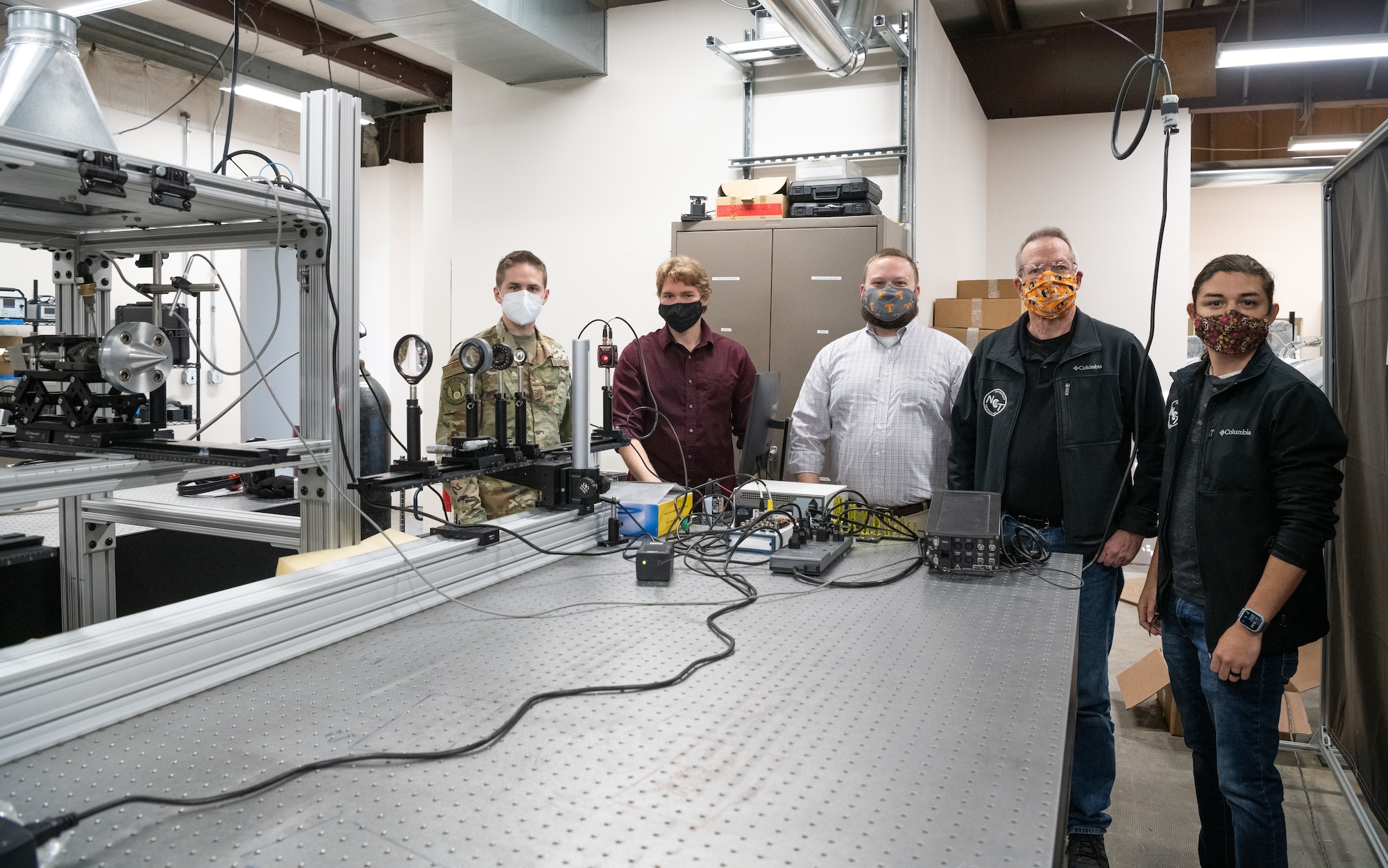 A team of engineers and small business representatives stand next to a focused laser differential interferometry setup at the University of Tennessee Space Institute.