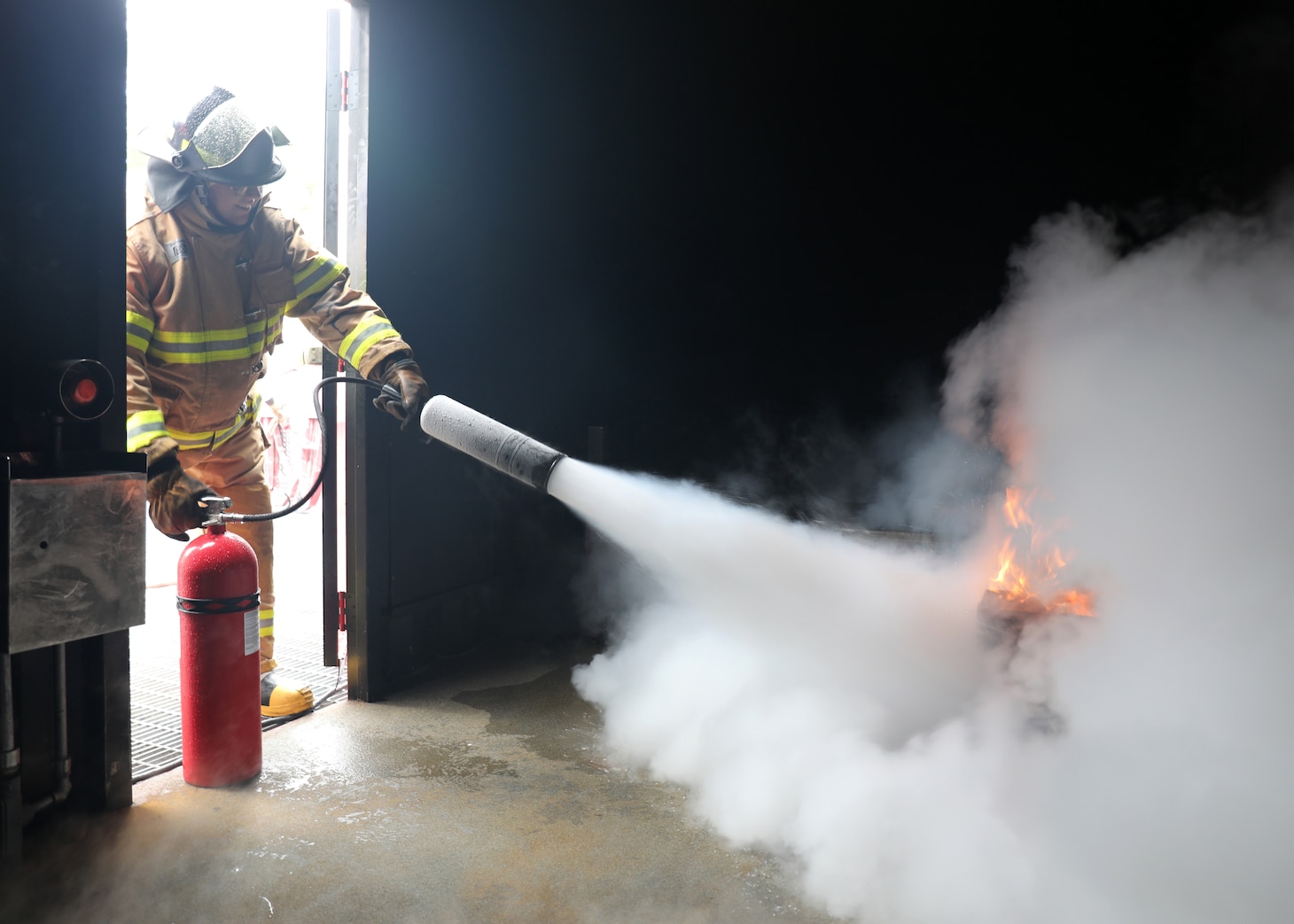 A newly hired Civil Service Mariner (CIVMAR) uses a CO2 fire extinguisher to put out a simulated trash can fire at the Military Sealift Command Training Center East on Joint Base Langley-Fort Eustis, Virginia, Feb. 23.