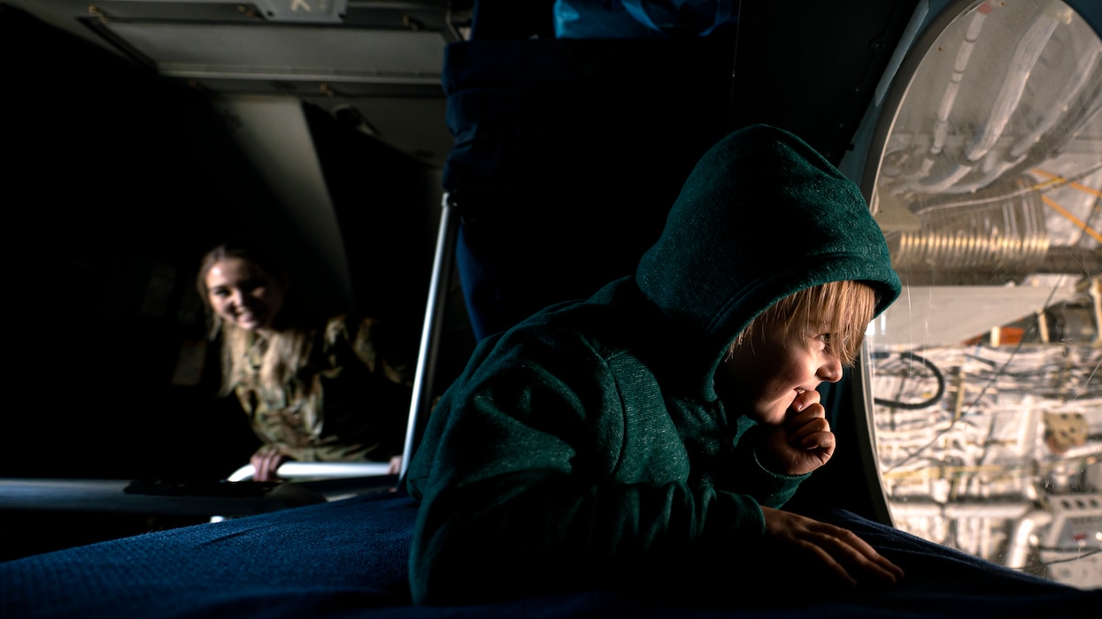 Photo of child on a military aircraft looking through a window