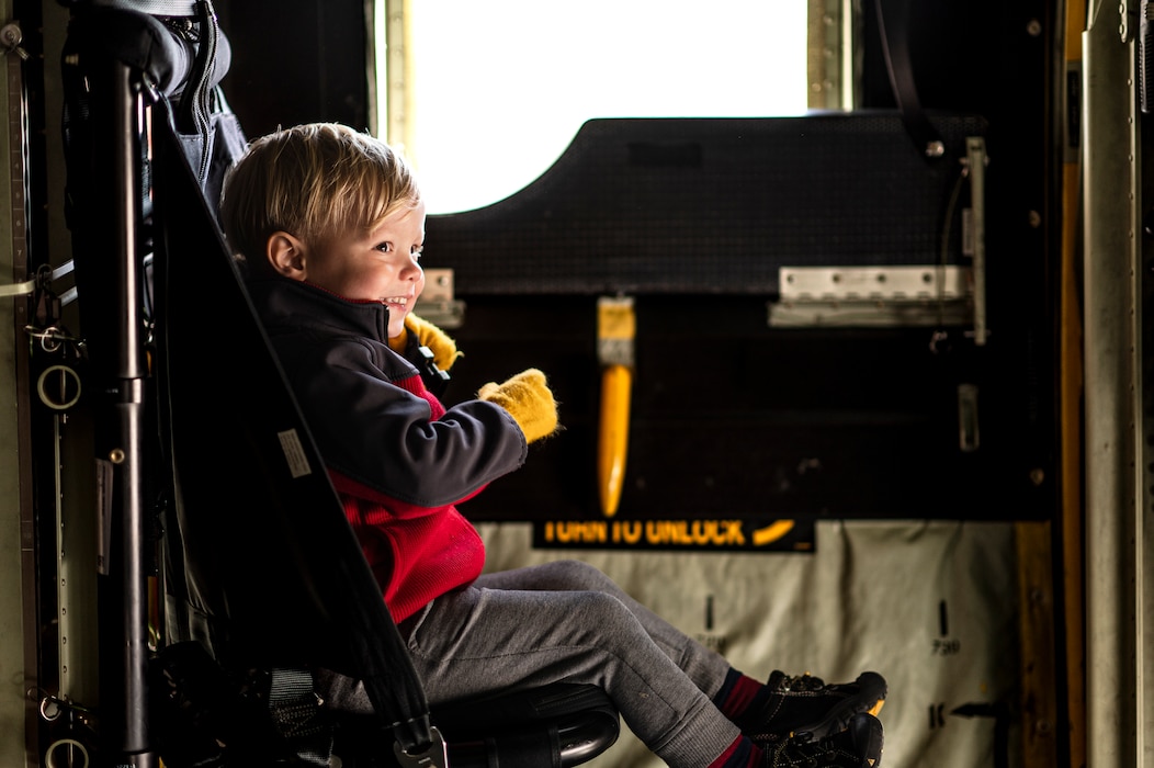 Photo of child sitting in a seat on a military aircraft