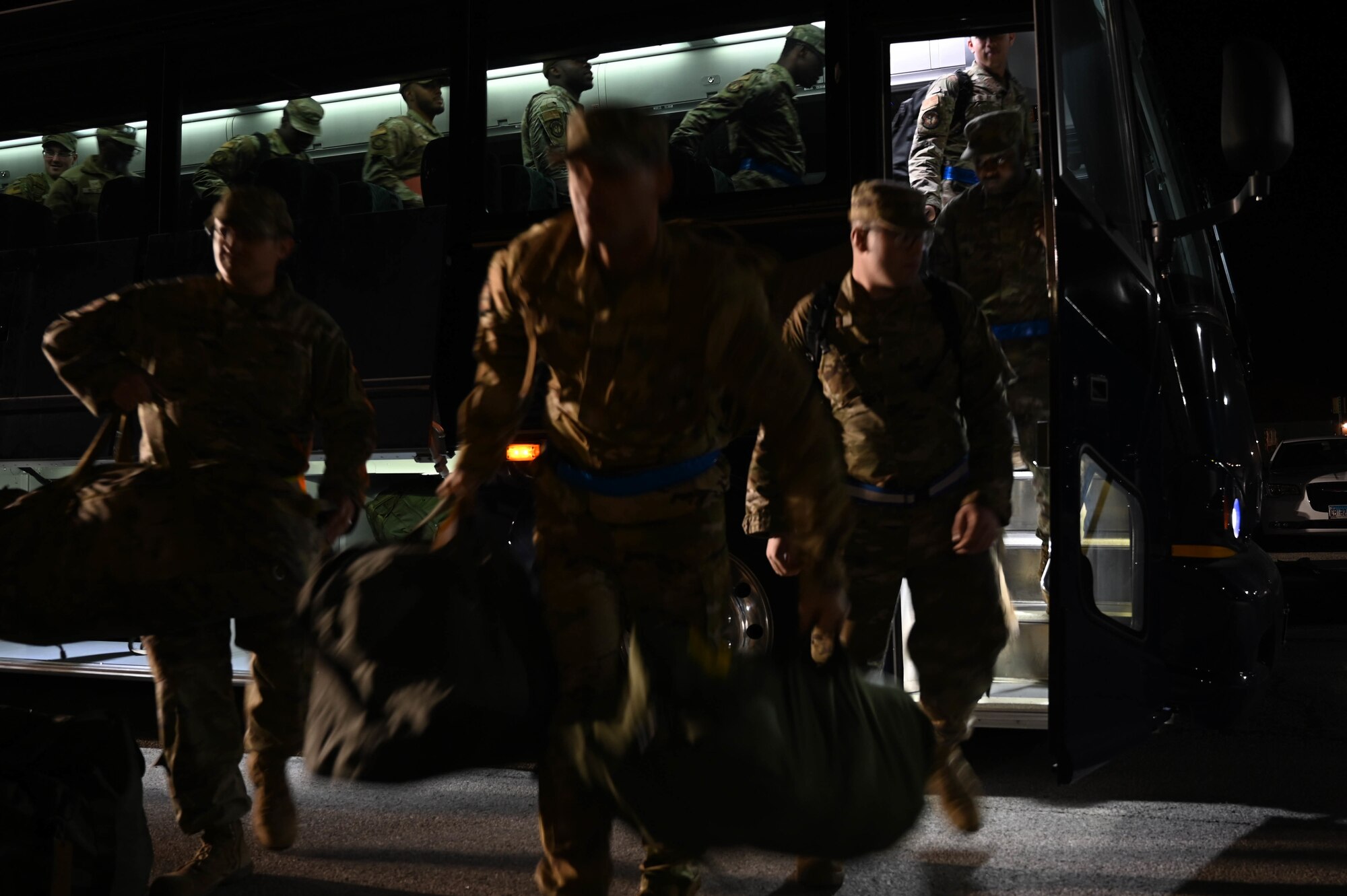 375th Civil Engineering Squadron Airmen rush to unload  from a bus during a rapid deployment rehearsal on Scott Air Force Base, Illinois, March 16, 2022. This deployment mobility rehearsal emphasizes readiness of command and control procedures and continuity of operations in a simulated contested environment. (U.S. Air Force photo by Airman 1st Class Mark Sulaica)