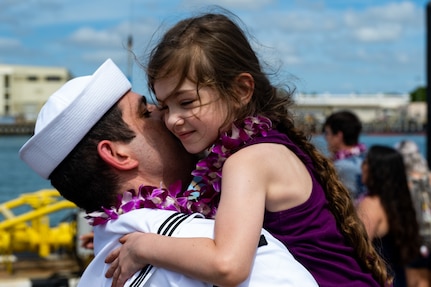 A Sailor reunites with his daughter on the submarine piers at Joint Base Pearl Harbor-Hickam after Minnesota completed a change of homeport from Groton, Conn., March 17, 2022.