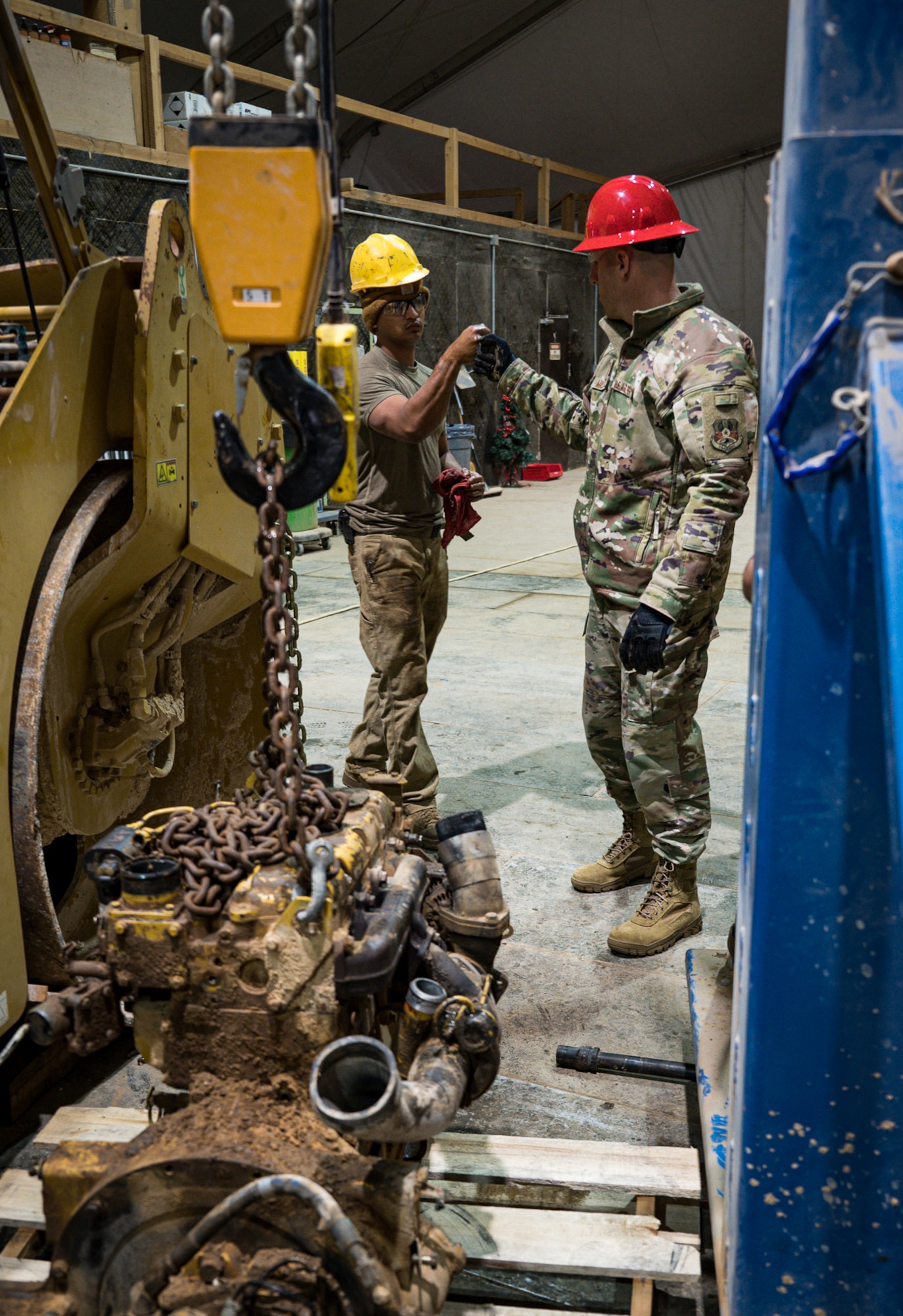 U.S. Air Force Chief Master Sgt. Sean Milligan, 332d Air Expeditionary Wing command chief, fist bumps Senior Airman Jesus Hernandez, 557th Expeditionary Red Horse Squadron vehicular equipment maintenance journeyman, after helping to remove an engine and hydraulic pump from a roller at an undisclosed location in Southwest Asia March 12, 2022. (U.S. Air Force photo by Master Sgt. Christopher Parr)