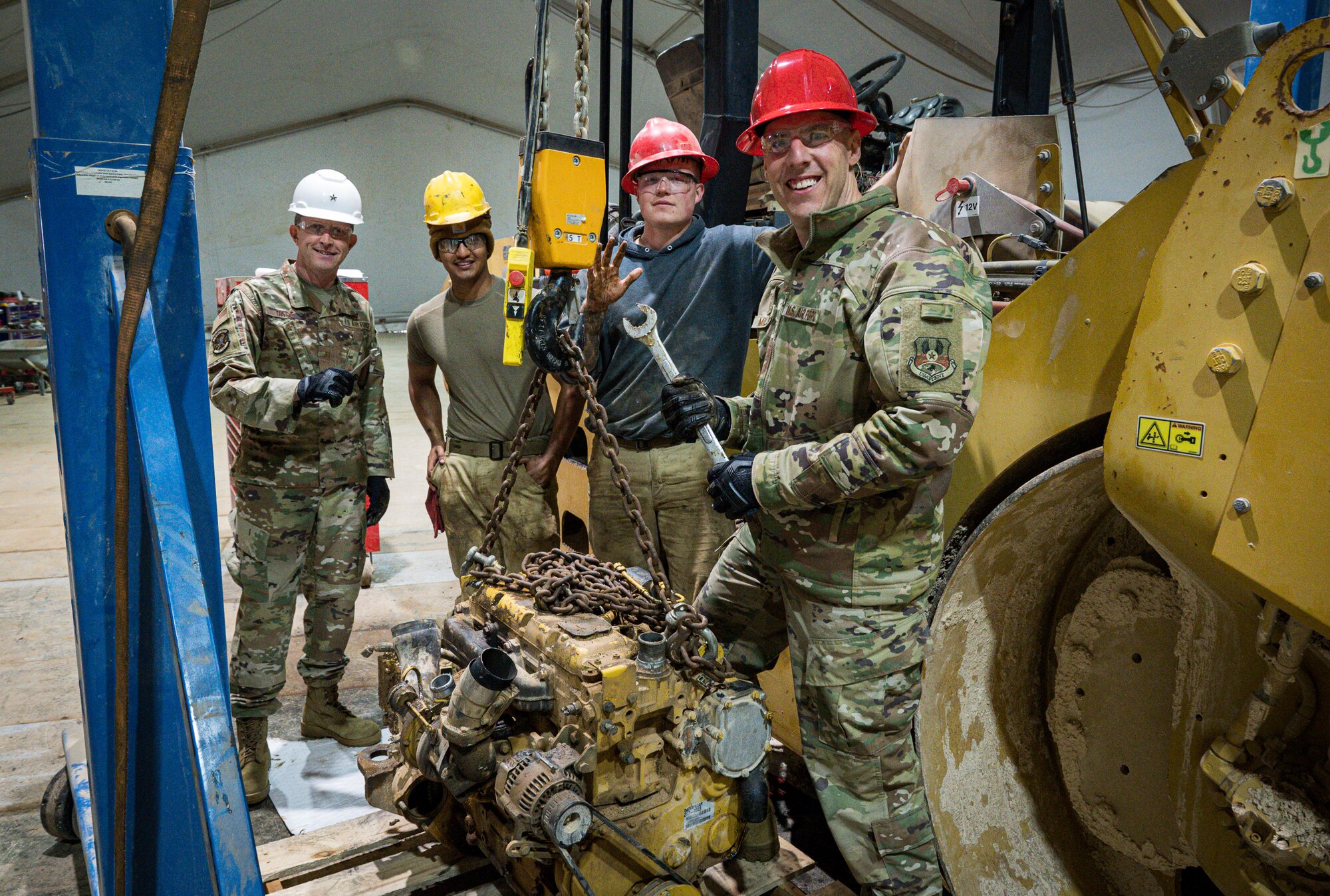 U.S. Air Force Brig. Gen. Christopher Sage, 332d Air Expeditionary Wing commander, left, and Chief Master Sgt. Sean Milligan, 332d AEW command chief, right, pose with Senior Airmen Jesus Hernandez and Tanner Henderson, both 557th Expeditionary Red Horse Squadron vehicular equipment maintenance journeyman at an undisclosed location in Southwest Asia March 12, 2022. (U.S. Air Force photo by Master Sgt. Christopher Parr)