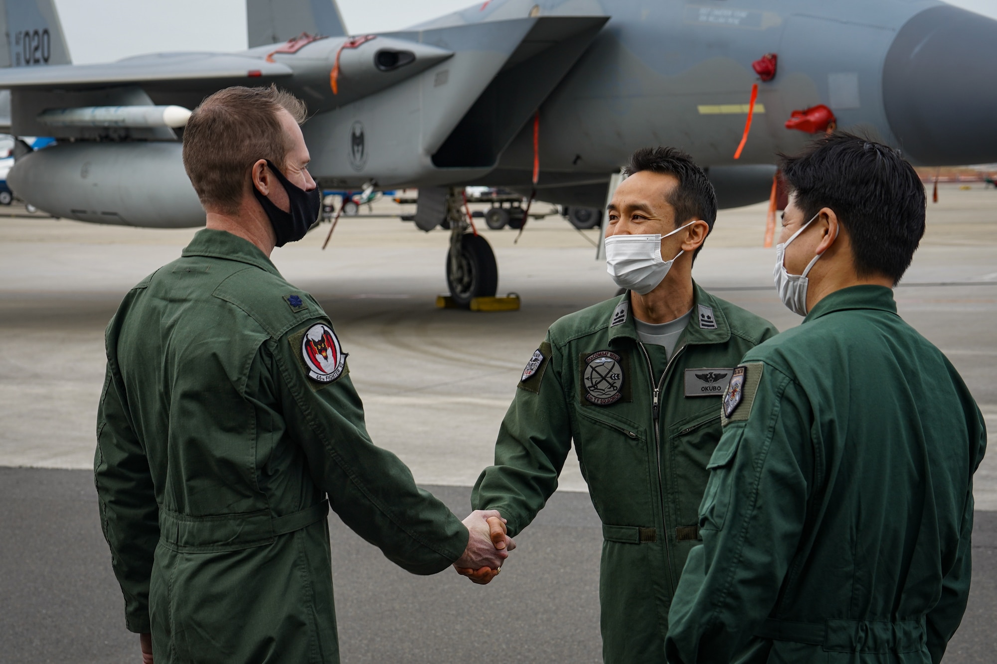 U.S. Air Force Lt. Col. William "Wild" Strohecker, 44th Fighter Squadron commander (left), shakes hands with Japan Air Self-Defense Force 6th Fighter Squadron commander (center), after a press conference on the first day of the aviation training relocation program, March 17, 2022. ATR is a result of the May 2006 United States-Japan roadmap for realignment implementation, a bilateral program aimed at increasing operational readiness and improving interoperability. (U.S. Air Force photo by Staff Sgt. Kyle Johnson)