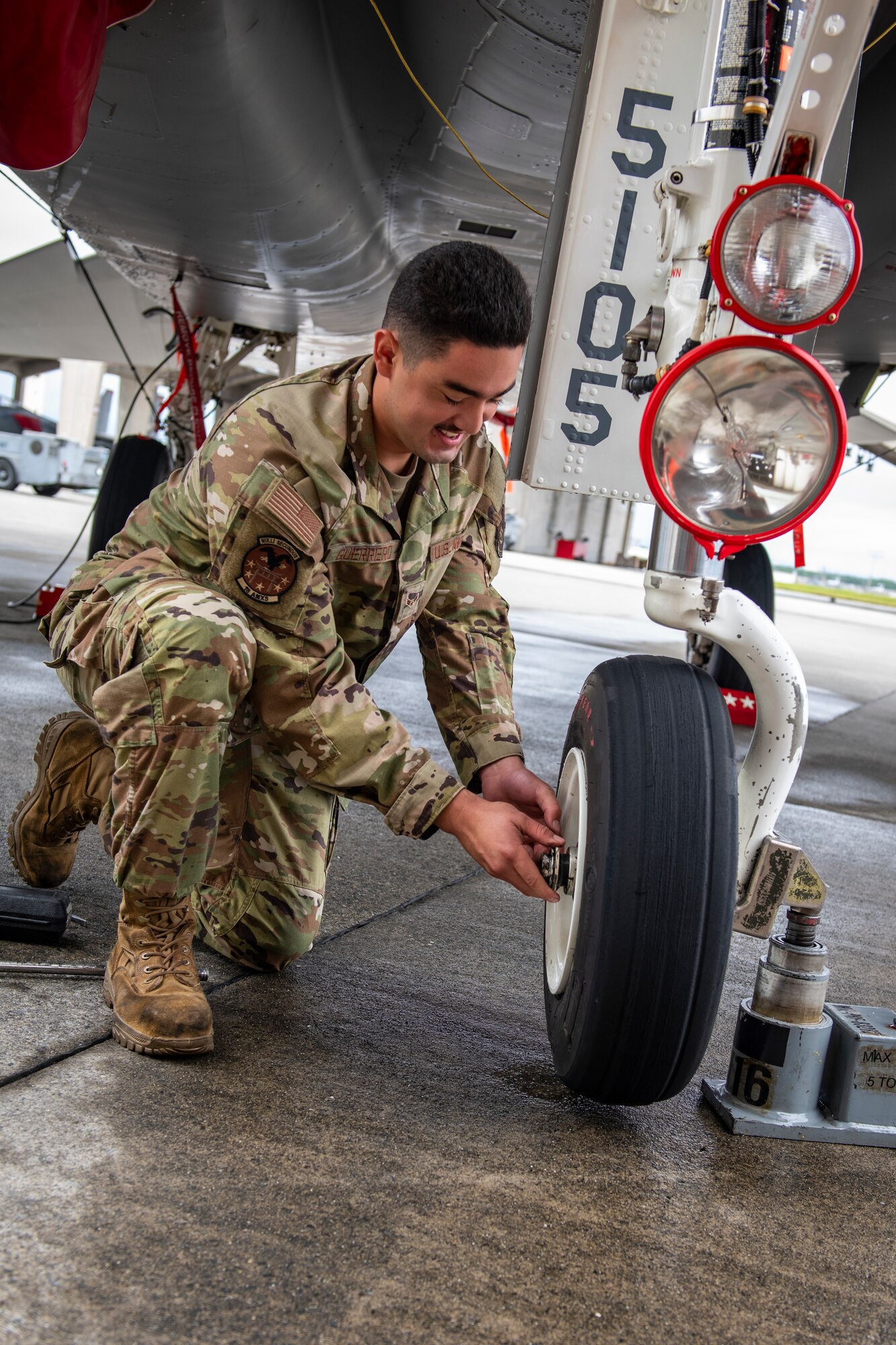 A maintainer changes a tire on an aircraft
