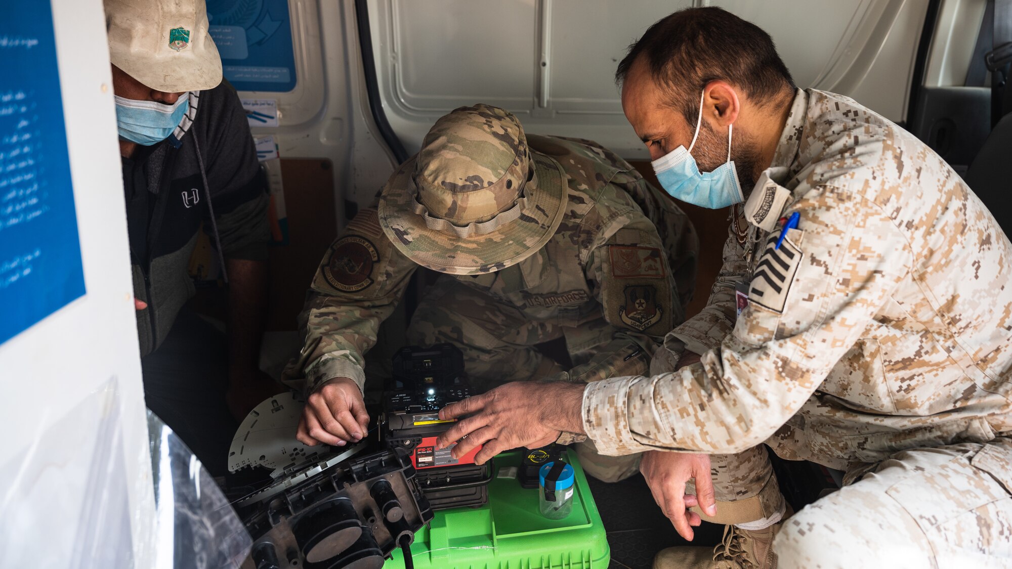 Airman 1st Class Keith Miller, 378th Expeditionary Communications Squadron cable and antenna systems technician, and service members from the Royal Saudi Air Force strip fiber optic strands at Prince Sultan Air Base, Kingdom of Saudi Arabia, March 17, 2022. The two services performed a fiber optic repair where they fused 24 fiber optic strands together. (U.S. Air Force photo by Senior Airman Jacob B. Wrightsman)