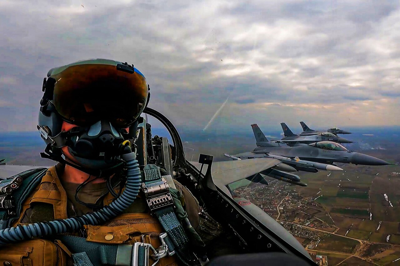 An Air Force pilot flying a F-16 Fighting Falcon fly alongside two Romanian F-16s.