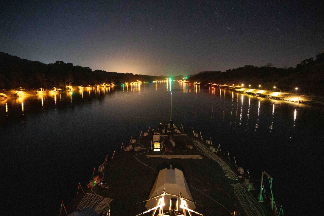 A ship travels through a canal at night.