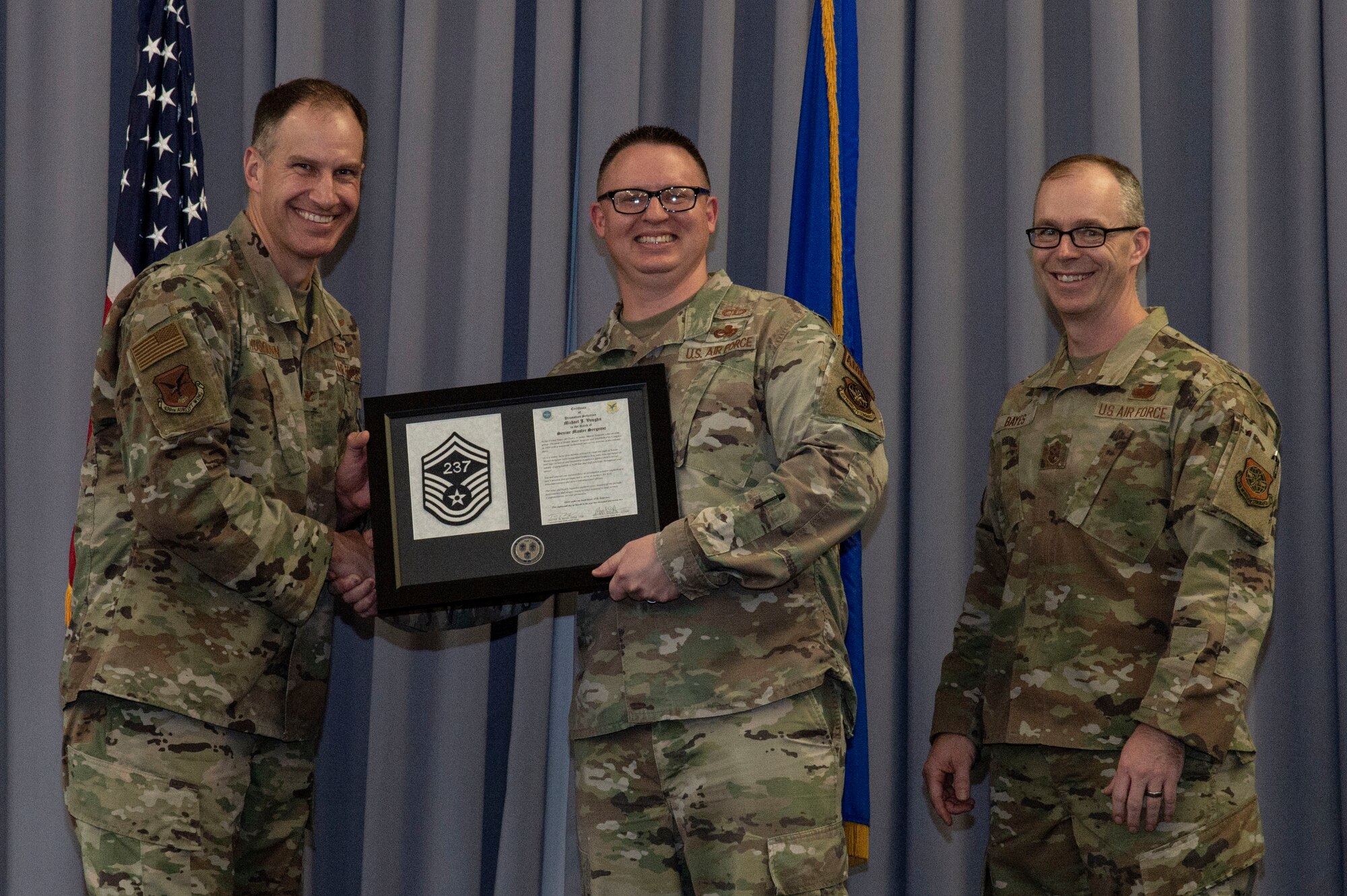 Master Sgt. Michael Vaughn, center, 436th Maintenance Squadron munitions flight chief, accepts his senior master sergeant promotion plaque from Col. Matt Husemann, left, 436th Airlift Wing commander, and Chief Master Sgt. Timothy Bayes, 436th AW command chief, during the senior master sergeant promotion release party at Dover Air Force Base, Delaware, March 18, 2022. Vaughn was one of seven master sergeants at Dover AFB selected for promotion to senior master sergeant in the 22E8 promotion cycle. (U.S. Air Force photo by Roland Balik)