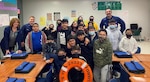Petty Officer 3rd Class Corey Connolly (left) and Petty Officer 2nd Class Daniel Noel, both Marine Safety Security Team (MSST) Houston Partnership in Education (PIE) volunteers, pose with students from Carter Lomax Elementary School in Pasadena, Texas during a Coast Guard career day. The PIE program unites the Coast Guard family with local schools and communities through opportunities to work directly with students which enhances educational opportunities and raises awareness about the Service (USCG Courtesy Photo).