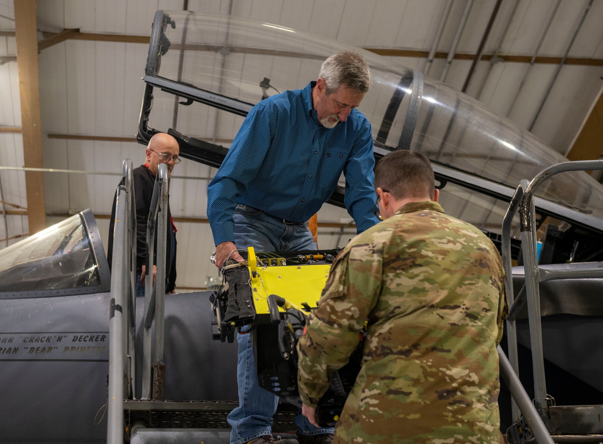 An Airman from the 4th Fighter Wing and an engineer contracted by the U.S. Air Force carry a component of a modular ejection seat prior to installing it on an F-15E Strike Eagle at Seymour Johnson Air Force Base, North Carolina, March 14, 2022. The modular seats are lighter and more mobile than previous ejection seat models. The Advanced Concept Ejection Seat 5 will replace the F-15E's older ACES II, which is used in many other aircraft in the U.S. Air Force’s arsonal.  (U.S. Air Force photo by Senior Airman Kevin Holloway)