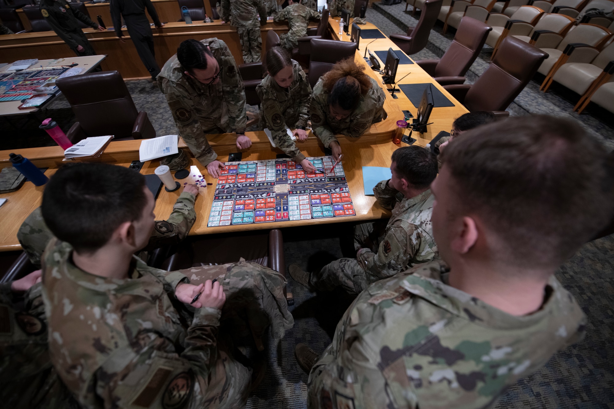 seven military members huddle around a board game