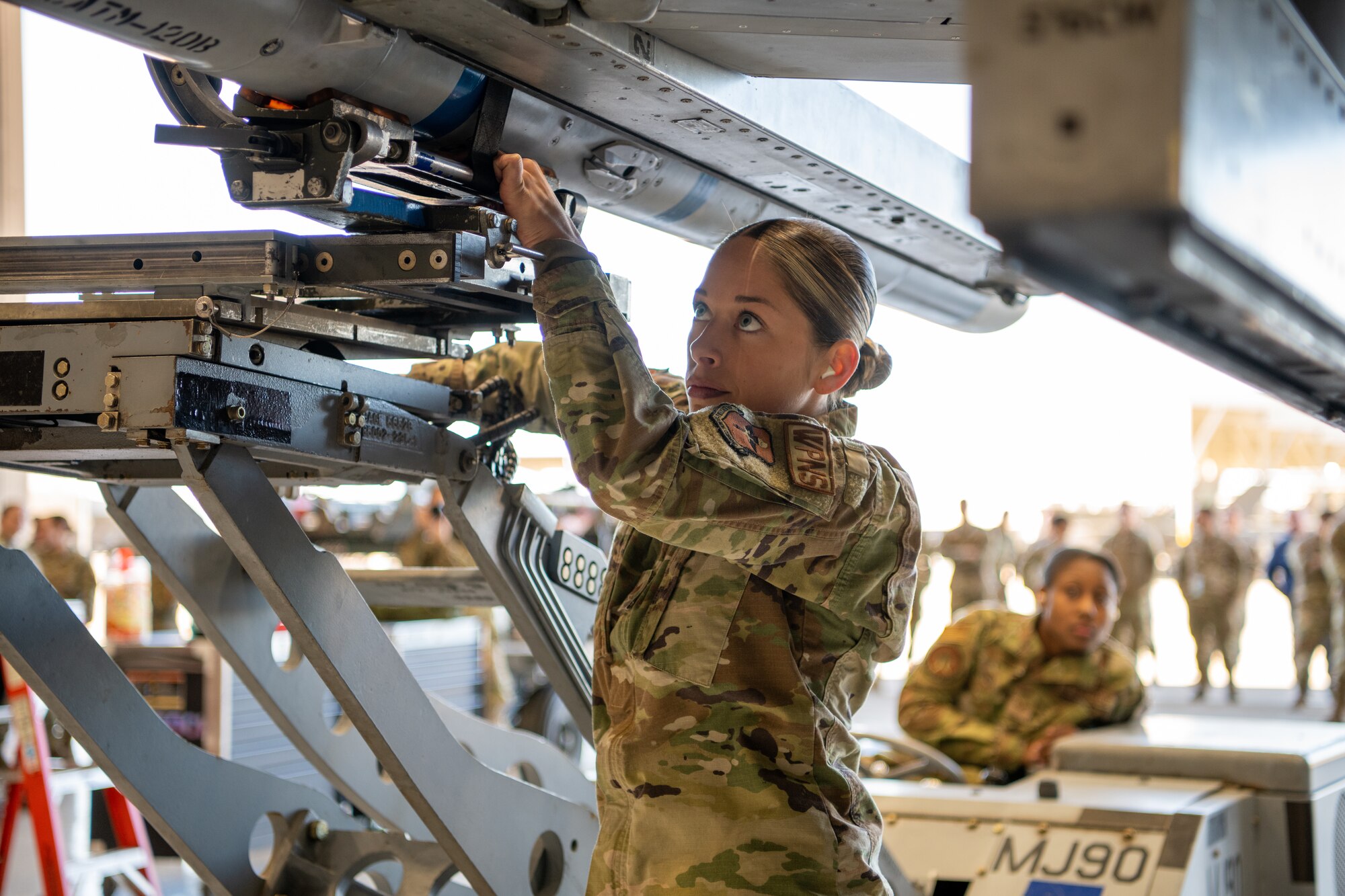 Staff Sgt. Quinn Ball, 310th Aircraft Maintenance Unit weapons load crew chief, loads munitions onto an F-16D Fighting Falcon during the Women of Weapons Load Exhibition March 11, 2022, at Luke Air Force Base, Arizona. The event was held in celebration of Women’s History Month to exemplify a culture of diversity and inclusion across the 56th Maintenance Group. (U.S. Air Force photo by Senior Airman Phyllis Jimenez)