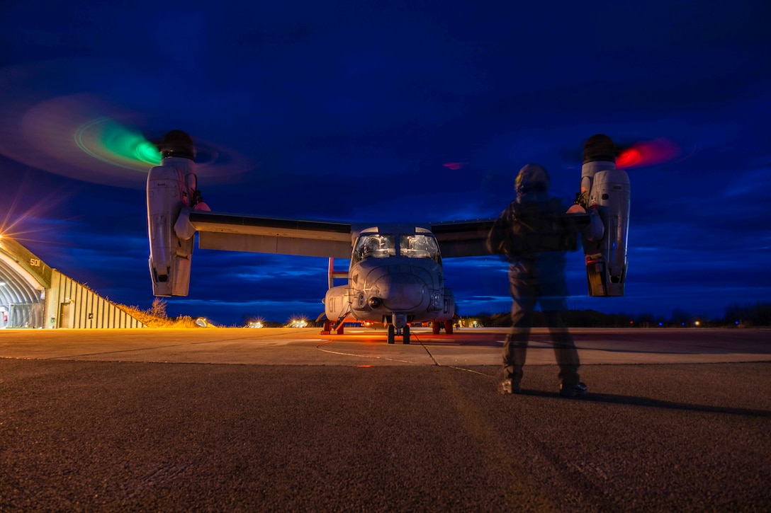 A Marine stands in front of a large aircraft.