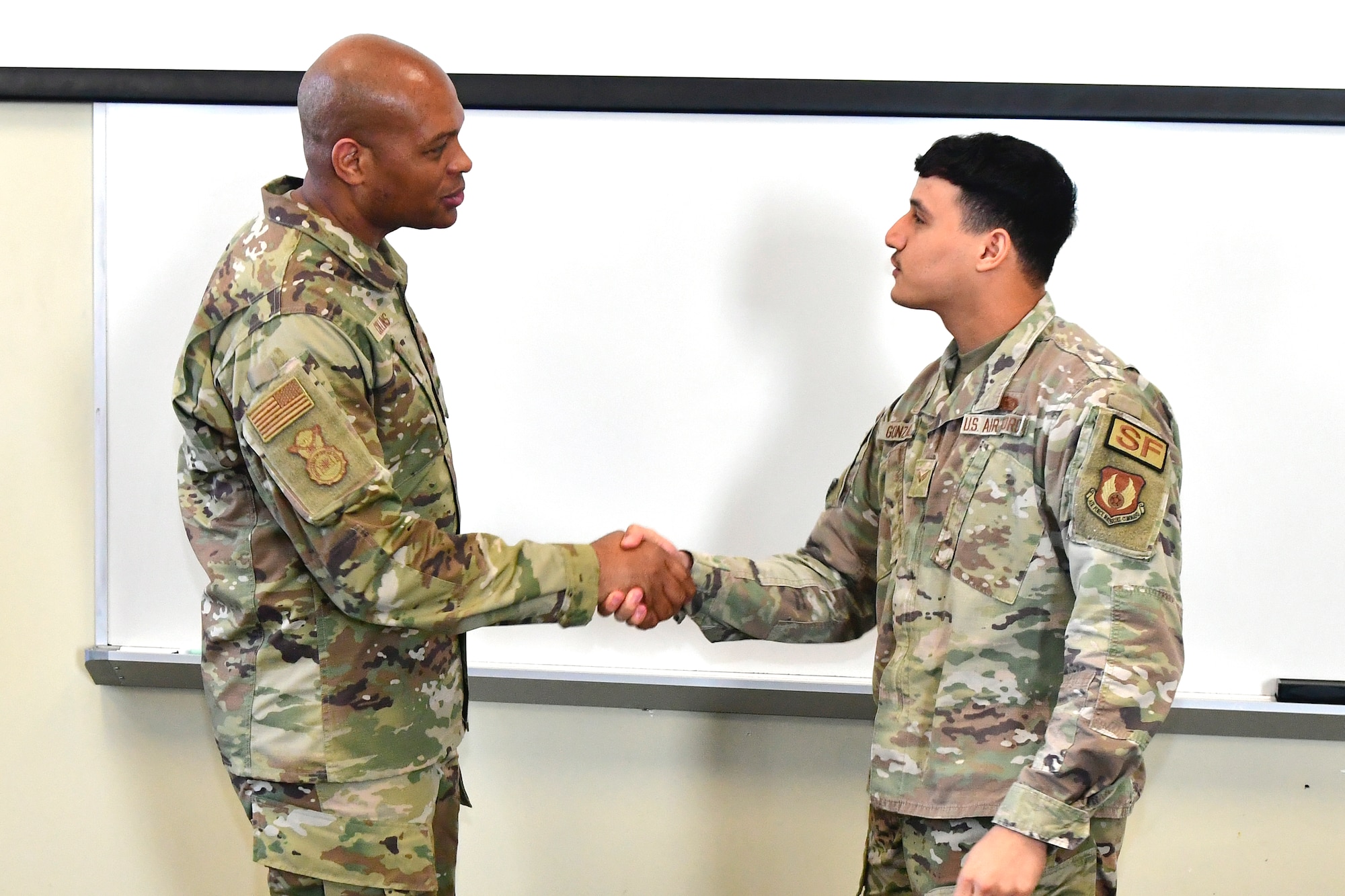 Brig. Gen. Roy Collins, Headquarters Air Force Security Forces director, shakes hands with Senior Airman William Gonzalez.