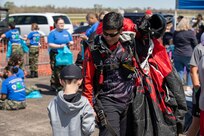 Sgt. 1st Class Jeff Menda, a parachutist with the United States Army Special Operations Command parachute team, the Black Daggers, greets a young bystander after landing at the Naval Air Station Joint Reserve Base New Orleans Airshow, March 19, 2022.