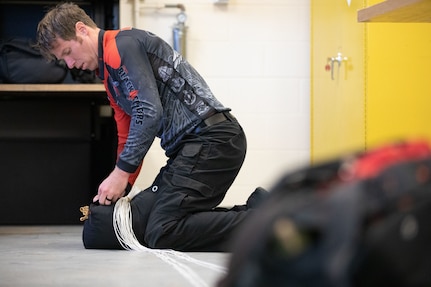 Master Sgt. Luke Whittington, a parachutist with the United States Army Special Operations Command parachute team, the Black Daggers, repacks his chute after a jump at Naval Air Station Joint Reserve Base New Orleans, March 19, 2022.