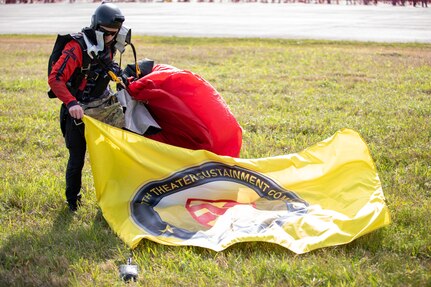 Sgt. 1st Class Michael Johnson, a parachutist with the United States Army Special Operations Command parachute team, the Black Daggers, collects his chute and flag after landing at Naval Air Station Joint Reserve Base New Orleans, March 19, 2022.