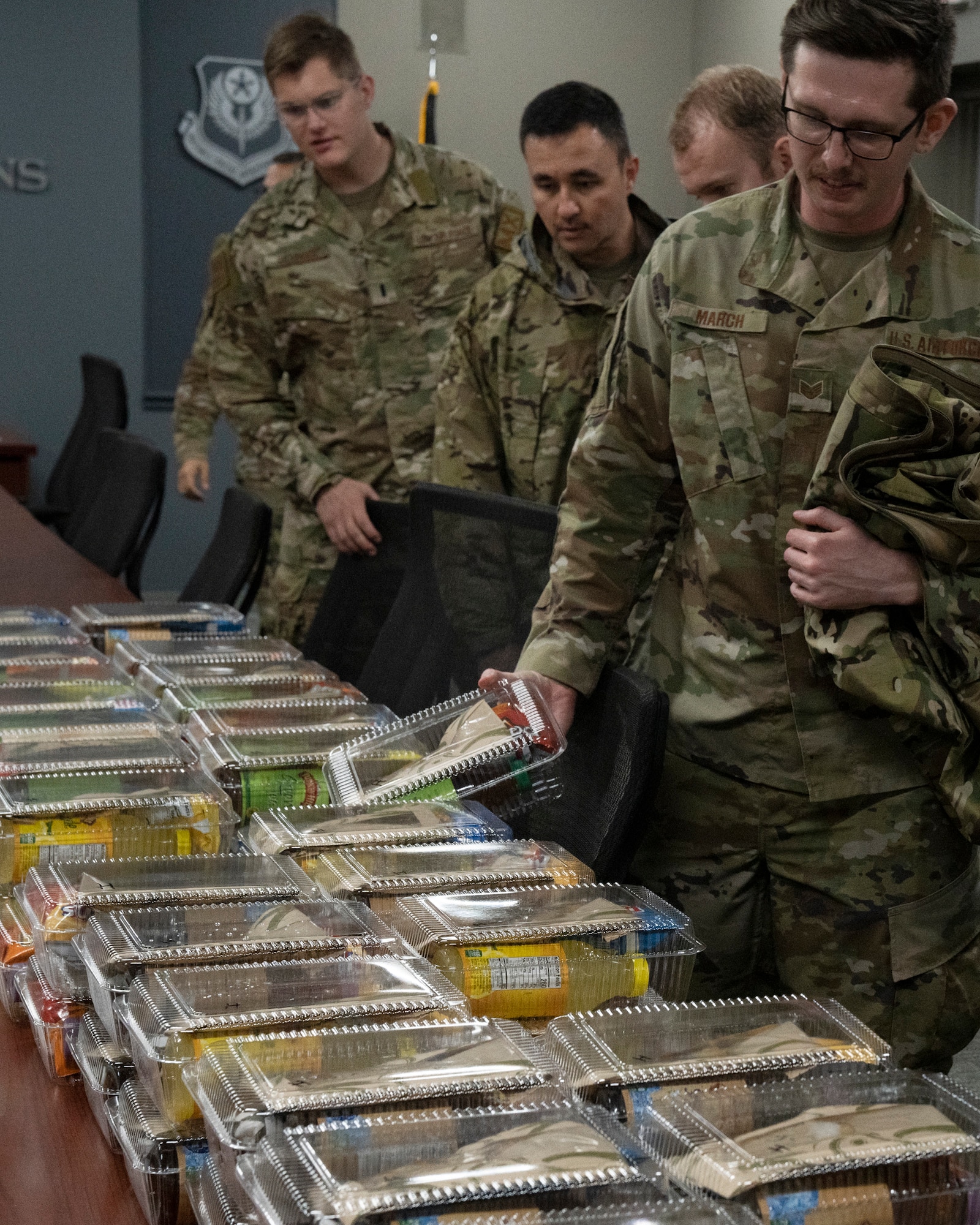 Airmen grab a boxed lunch on a table