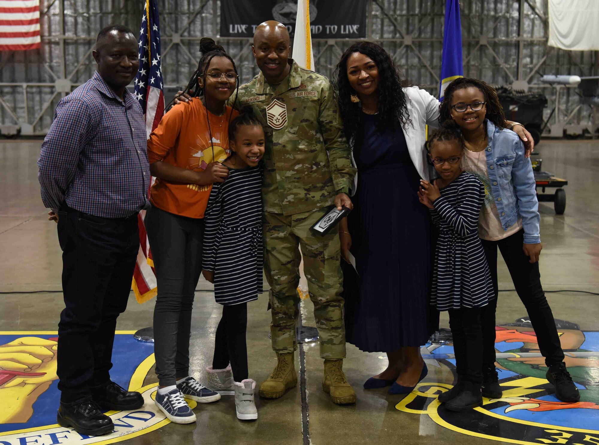 A military member holds up his promotion with friends, family and coworkers