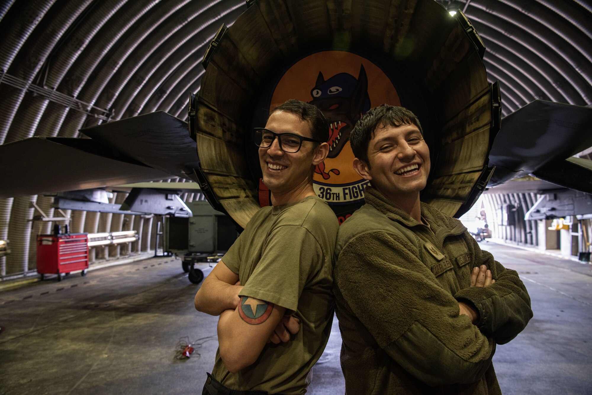 Staff Sgt. Armando Sutton, 36th AMU F-16 dedicated crew chief, left, and Tech. Sgt. Jose Corral DeLeon, 36th Aircraft Maintenance Unit cannibalization manager, right, stand proudly in front of their squadron logo displayed on an F-16 Fighting Falcon at Osan Air Base, Republic of Korea, March 17, 2022.