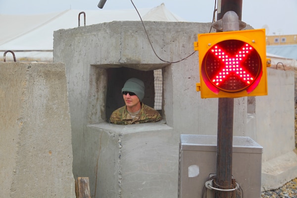 A service member stands inside a concrete bunker.