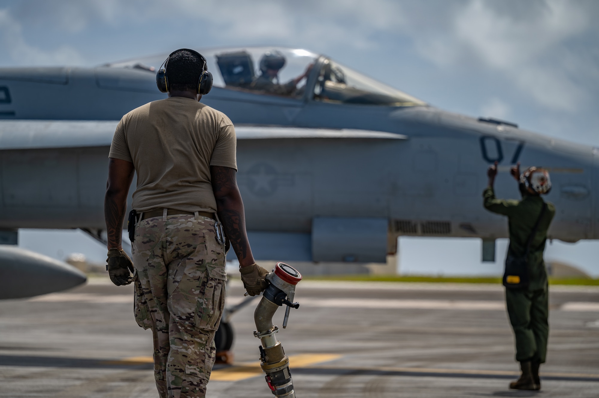 A 40th Airlift Squadron loadmaster prepares to attach a fuel hose to a Marine Fighter F/A-18C Hornet at Andersen Air Force Base, Guam, Feb. 14, 2022.