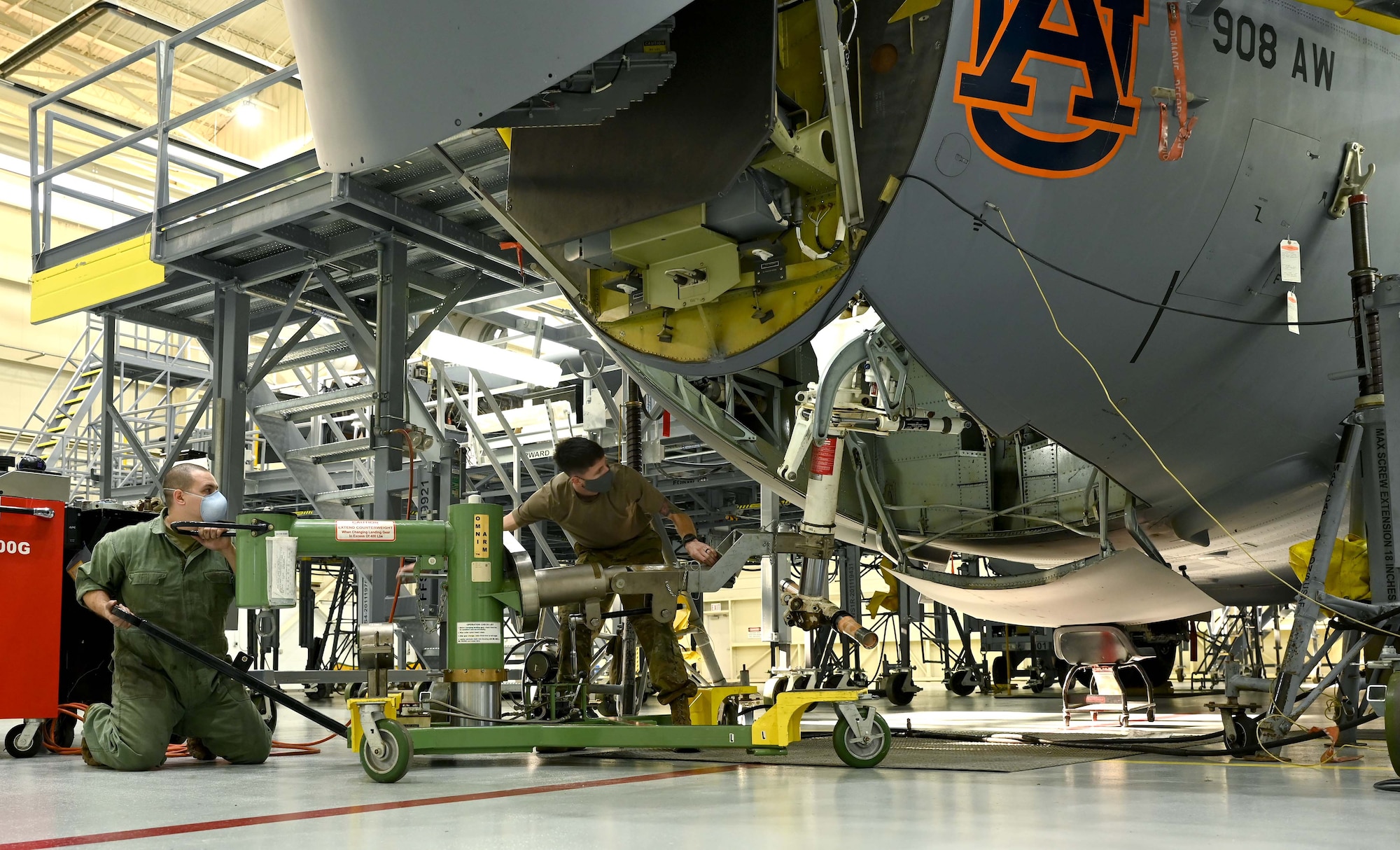 two men use equipment to remove landing gear