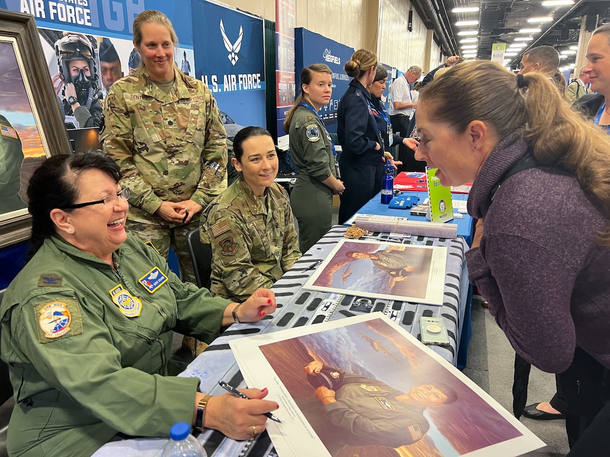 U.S. Air Force Reserve 2nd Lt. Kat Justen, Air Force Reserve Command Office of History and Heritage combat artist, smiles and talks with conference attendees while signing autographs.