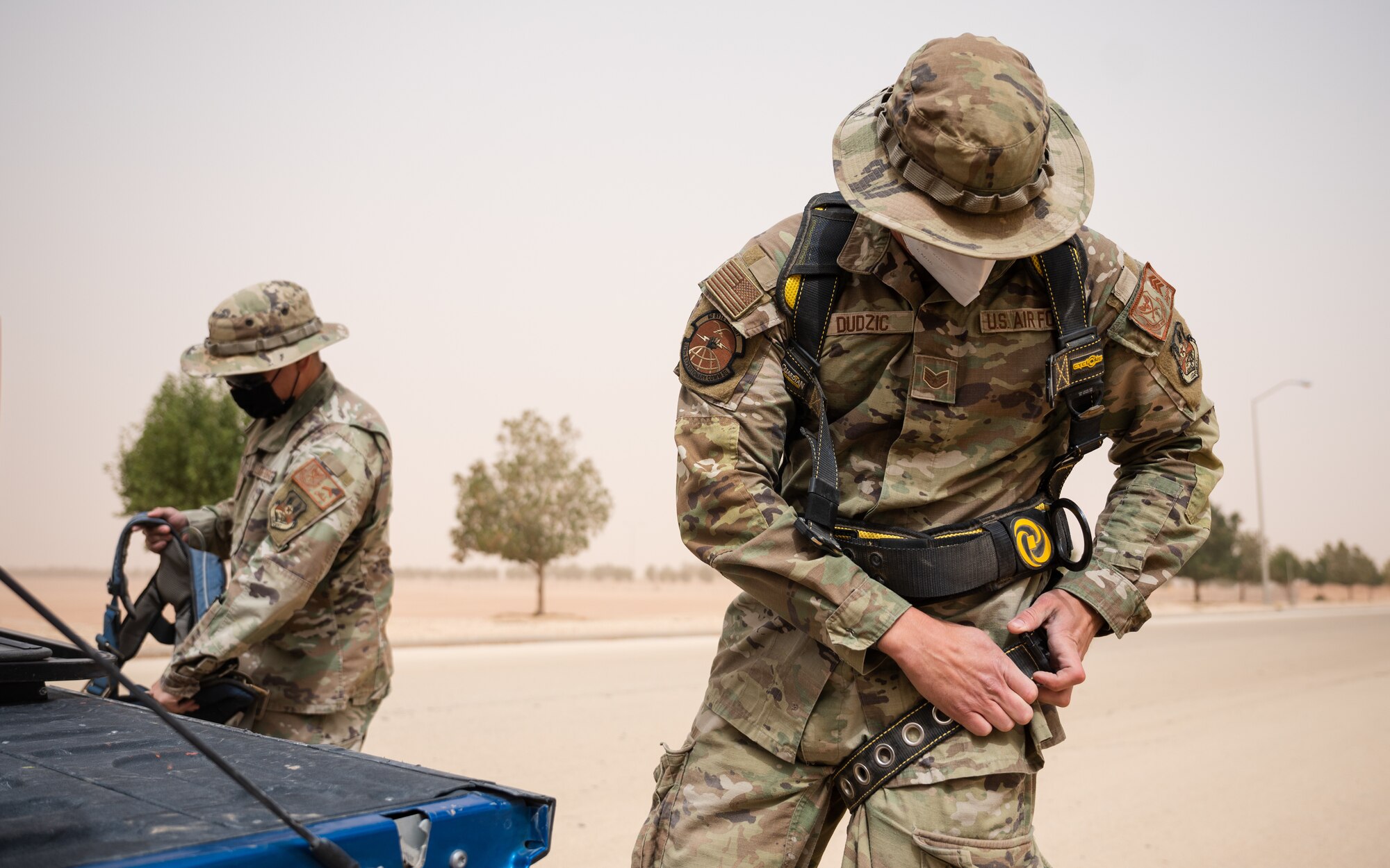 Airman 1st Class Keith Miller and Staff Sgt. Norbert Dudzic, 378th Expeditionary Communications Squadron cable and antenna systems technicians, don their safety harnesses prior to a fiber optic repair at Prince Sultan Air Base, Kingdom of Saudi Arabia, March 17, 2022. The 378th ECS performed the repair alongside their Royal Saudi Air Force counterparts, strengthening the interoperability between the two services. (U.S. Air Force photo by Senior Airman Jacob B. Wrightsman)