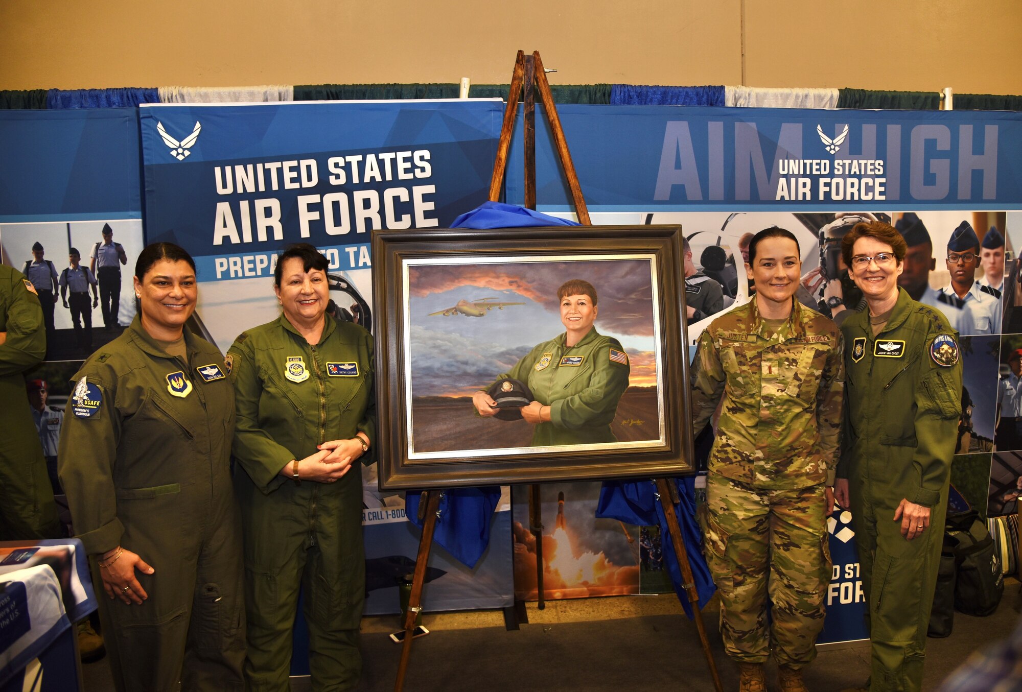 A group of influential female Airmen pose for a group photo next to a fine art painting of another female Airman.