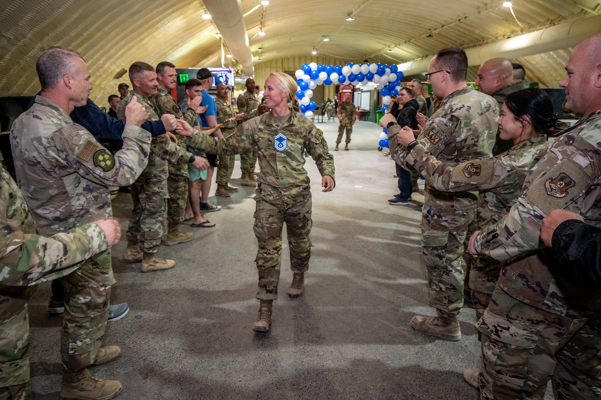 Master Sgt. Cassandra Moore, 55th Expeditionary Fighter Generation Squadron, walks toward the stage receiving congratulatory fist bumps from fellow Red Tails at the 332d Air Expeditionary Wing senior master sergeant release party March 19, 2022, at an undisclosed location in Southwest Asia. Moore was one of six senior master sergeant selects from the 332d AEW and one of 1,433 selects for the Air Force. (U.S. Air Force photo by Master Sgt. Christopher Parr)