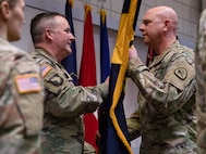 Command Sgt. Maj. Richard Brown passes the 97th Troop Command colors to Col. Tammy Manwaring during the change-of-command ceremony
