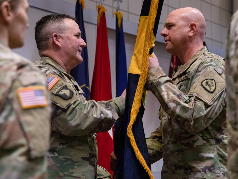 Command Sgt. Maj. Richard Brown passes the 97th Troop Command colors to Col. Tammy Manwaring during the change-of-command ceremony