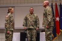 Col. Tammy Manwaring and Lt. Col. Eric Wiedmeier prepare to pass the 97th Troop Command colors during a change-of-command ceremony