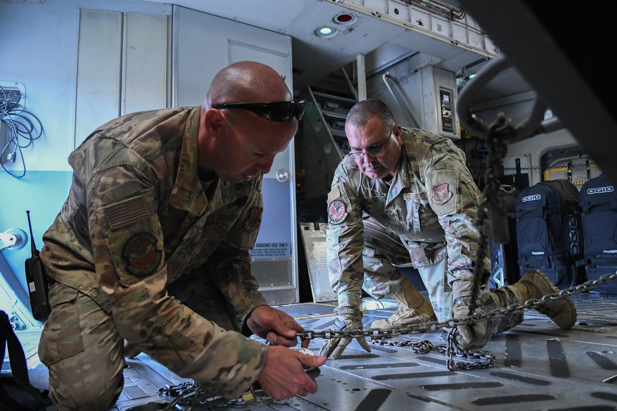 Tech Sgt. Nathan Edwards, 920th Logistics Readiness Squadron aerial porter, ties down rolling stock with chains on an aircraft at Patrick Space Force Base, Fla., Mar 11 2022. (U.S. Air Force photo by Staff Sgt. Darius Sostremiroir)