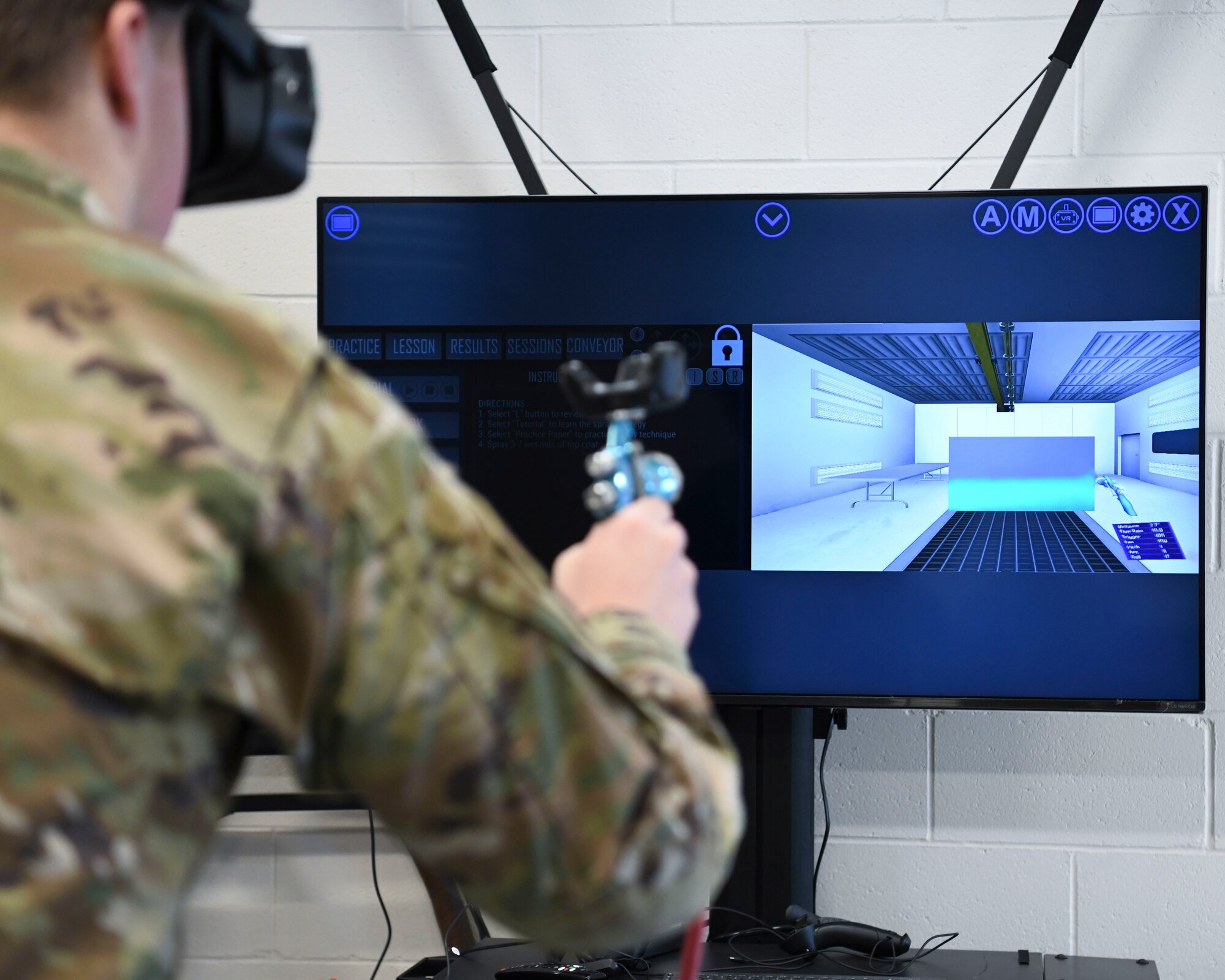 The photo is taken looking over an Airman's shoulder as he uses the virtual reality painting booth for his training.