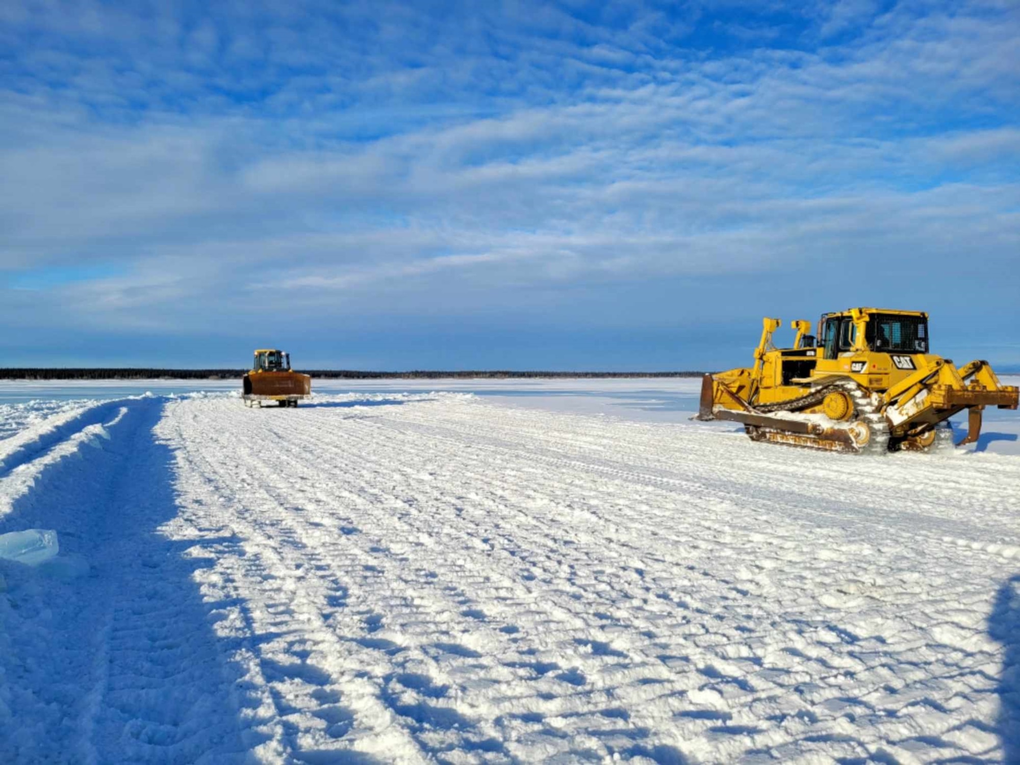 Mike Lenze, 354th Range Squadron, and Tech. Sgt. Jajuan Richards, 9th Civil Engineer Squadron heavy equipment, drive parallel to one another to break down large pieces of ice
