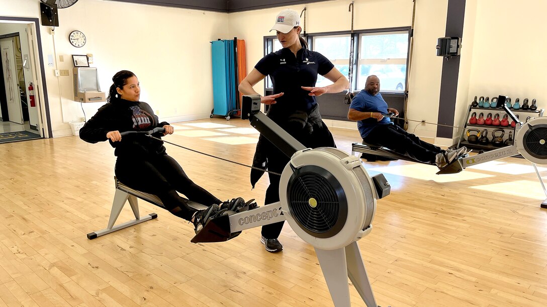 Wounded warrior works with coach during rowing practice.