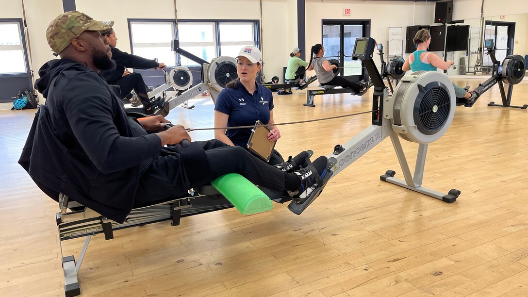 Wounded warrior works with a coach during indoor rowing practice.