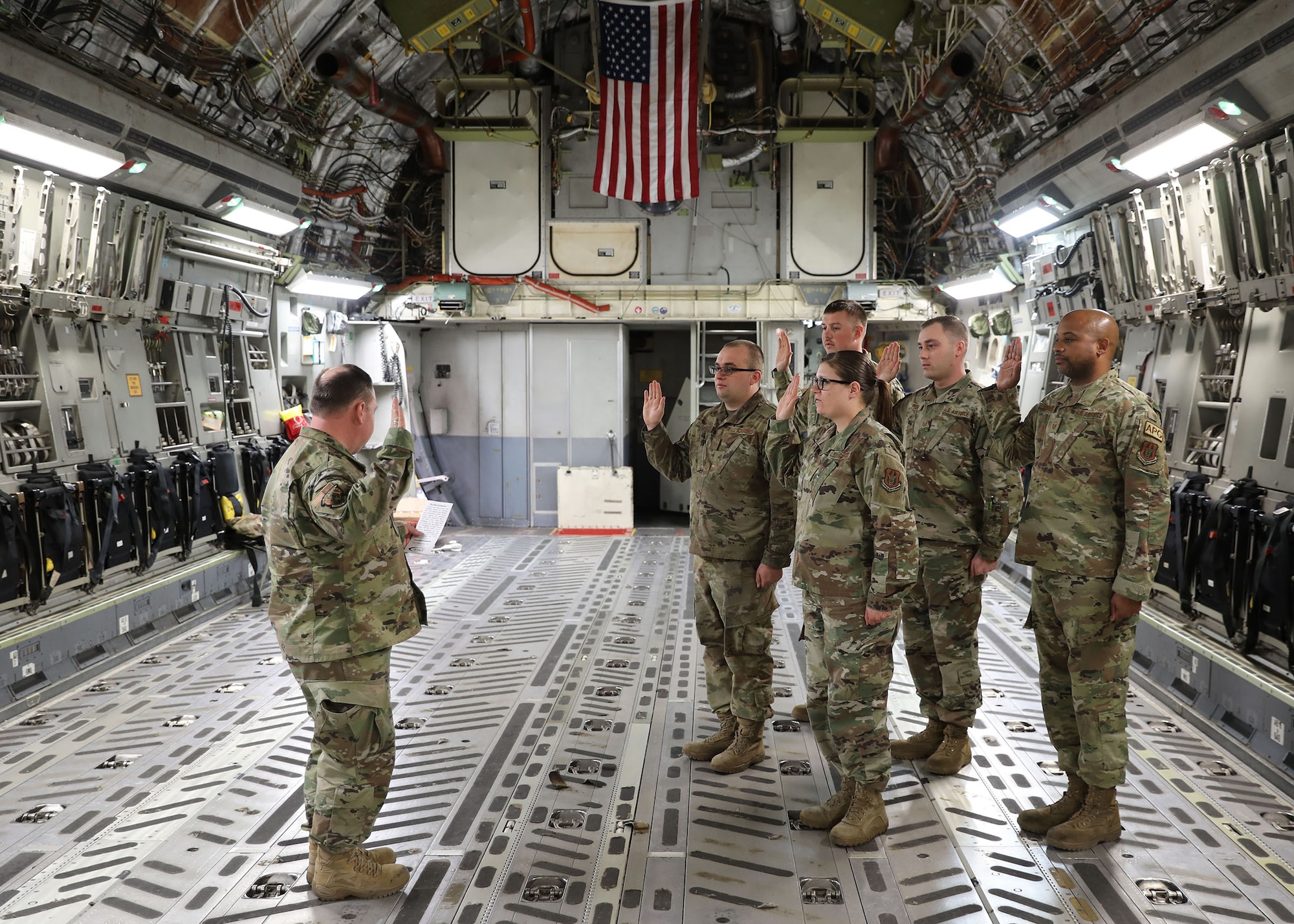 Lt. Col. Michael Shutt, the commander of the 445th Aircraft Maintenance Squadron, conducts a re-enlistment ceremony for several AMXS Airmen on March 13, 2022 at Wright-Patterson Air Force Base, Ohio. The ceremony was held in the aft section of a C-17 Globemaster III aircraft and involved the Airmen pledging additional service commitments to their country.