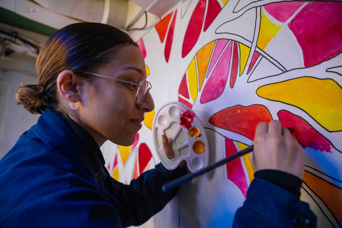 A sailor paints on a wall.