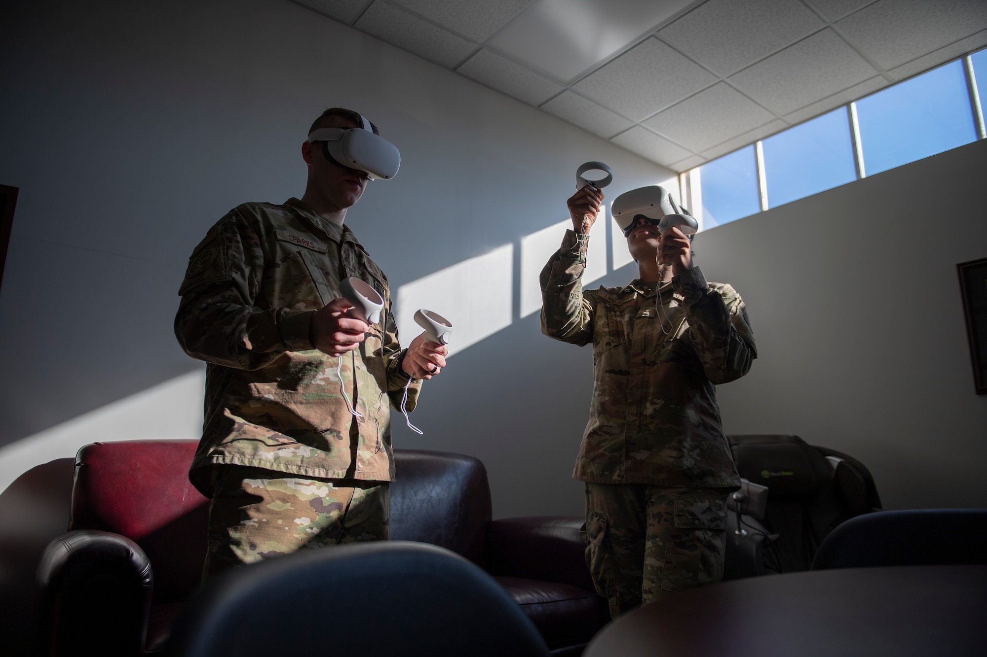 A photo of two Airmen standing in the middle of a room with VR headsets on.