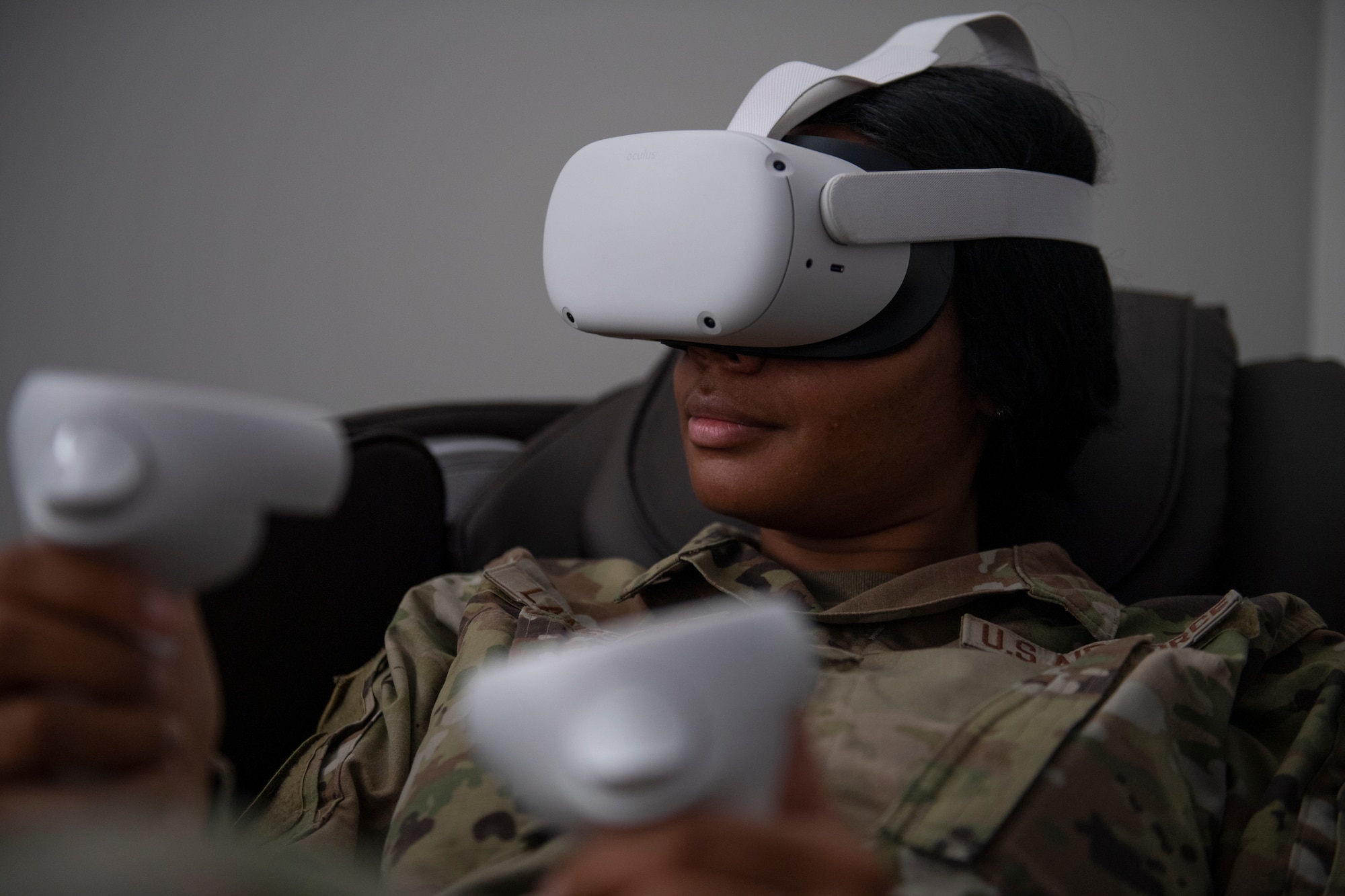 A photo of a female Airman with a VR headset on and holding the controls.