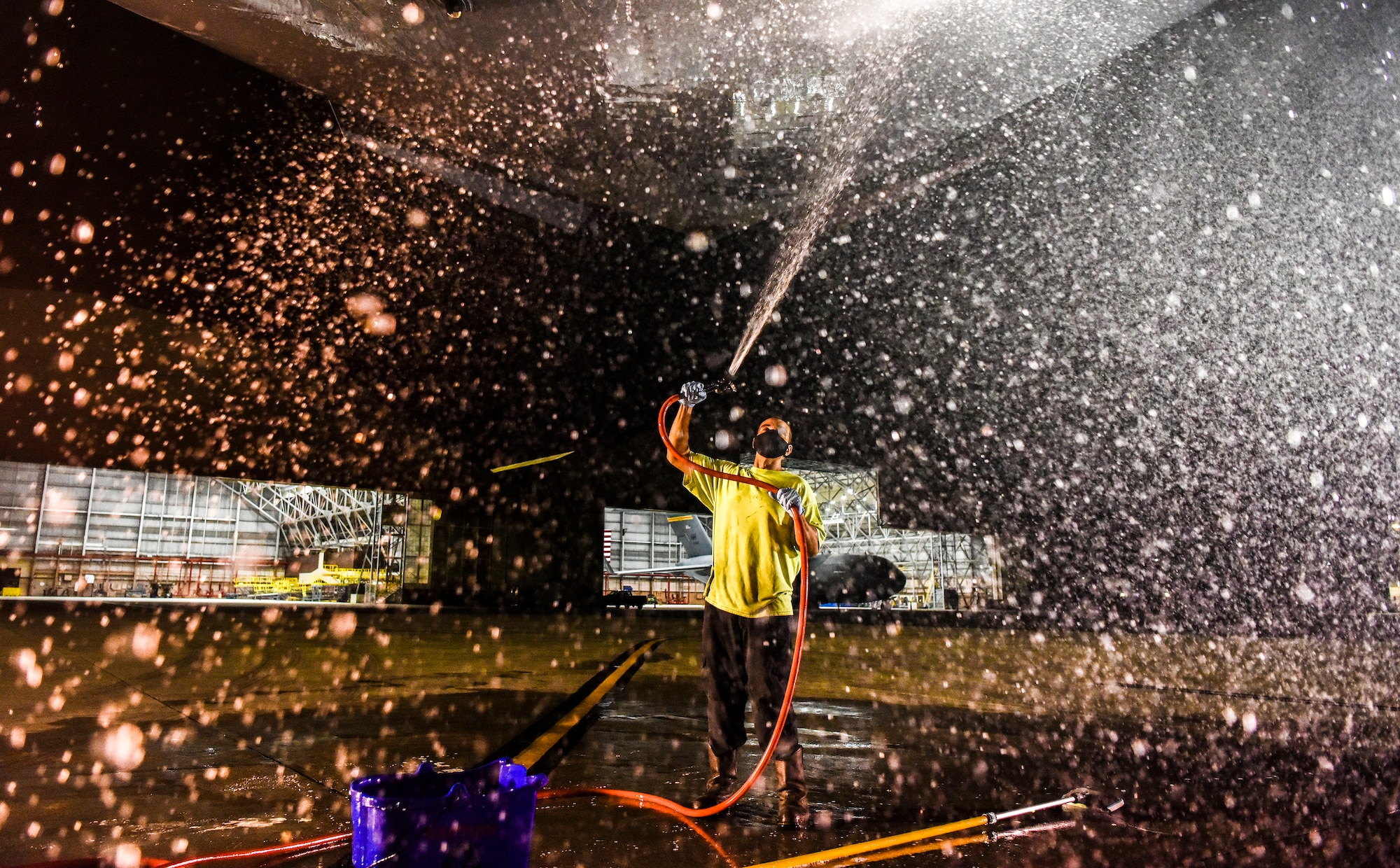 A contractor with the 15th Aircraft Maintenance Squadron rinses off soap from under a U.S. Air Force C-17 Globemaster III  at Joint Base Pearl Harbor-Hickam, Hawaii, Jan. 7, 2020.